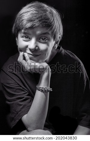 black and white portrait of a smiling male teenager with black background.
