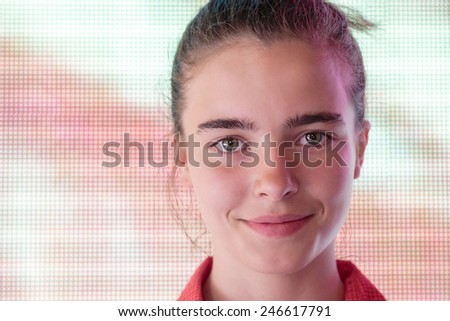 portrait of a smiling teenage girl in front of a digital screen