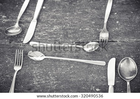black and white shot of some vintage silverware on an old table