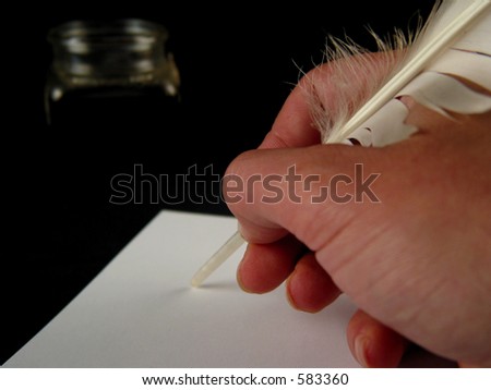 Close-up of hand holding a feather writing on white paper with ink (black background)