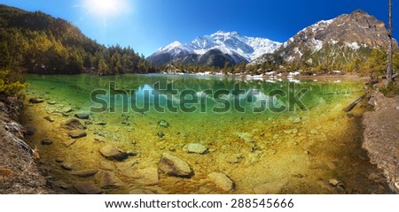 Beautiful mountain lake with crystal clear water surrounded by hills and mountains.  Nepal, Annapurna region, Mring lake (3,270 m) and Annapurna II (7,937 m)