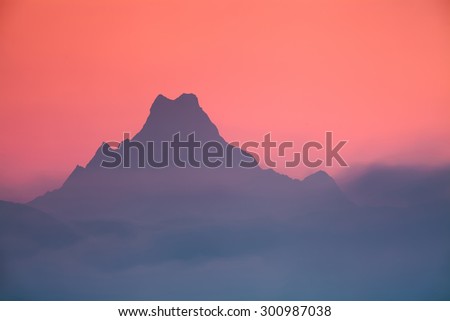 Silhouetted mountains peak in purple haze. Mount Machapuchare (6,997 ?) - one of the most famous unclimbed peaks in the world.