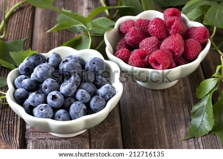 Fresh berries in bowls on Wooden Background, raspberry and blueberry