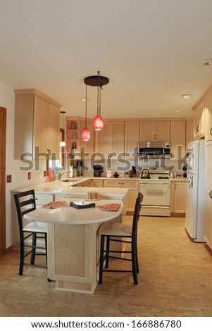 Kitchen interior with updated maple wood cabinetry cork floors and quartz countertops under pendant lights
