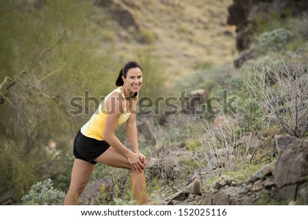 Young woman streching to warm up for a trail run outdoors at South Mountain Park in Phoenix, Arizona.