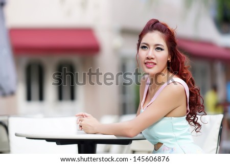 Beautiful young woman sitting alone in street cafe, Model is Thai Ethnicity.