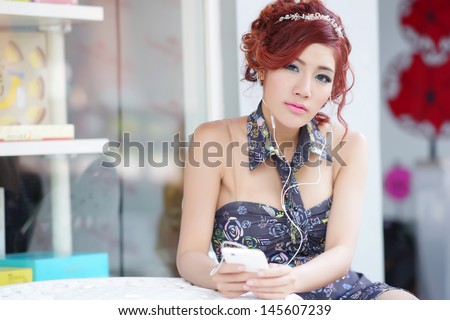 Beautiful woman using smartphone listen melancholic music while sitting at outdoor cafe, model is Thai Ethnicity,