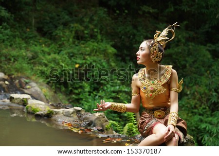 Beautiful Thai lady in Thai traditional drama dress, posing in the forest, greenery in the background, model is Thai Ethnicity.