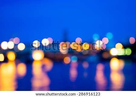 View of night light blur with reflection light in water on twilight background at bridge in Bangkok, Thailand