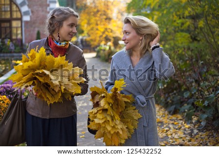 beautiful women with maple leafs walking in the park
