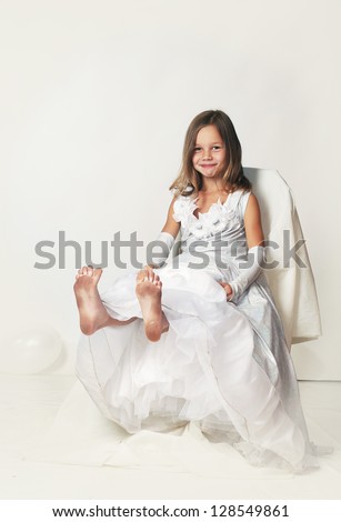 little sly girl sitting in white dress showing her dirty feet