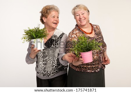 two senior woman friends studio portrait with plants in the pot isolated on white