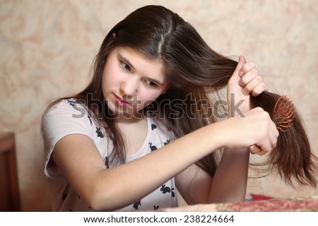 beautiful teen girl try to comb her long dark thick hair