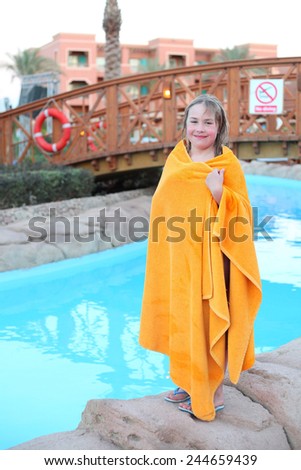 little blond girl in yellow towel after swimming in egyptian water park pool