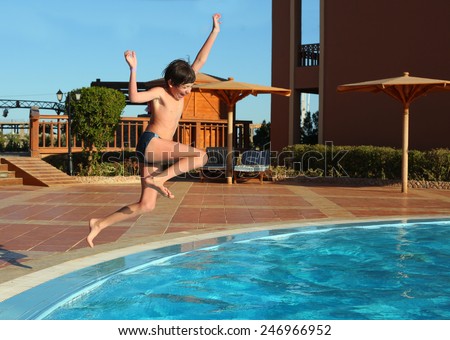 preteen boy jump into the open air swimming pool