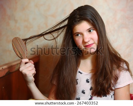 beautiful teen girl try to comb her long dark thick hair