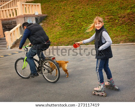 father drive his preteen beautiful daughter on roller skates by bicycle