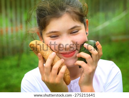happy teenager girl with natural healthy food - grain bread loaf and avocado on the green country garden background