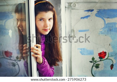 beautiful teen girl look out of the balcony window on the wall drawing of red rose background
