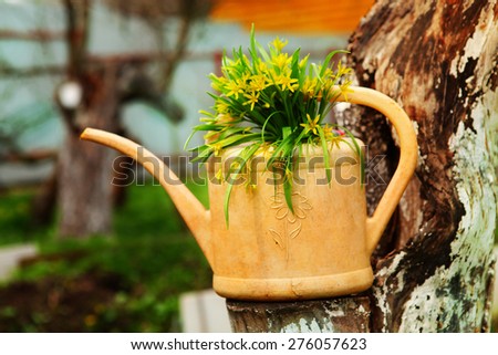 cure idea for garden landscaping yellow flowers in plastic watering can on the apple tree