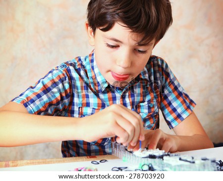 preteen handsome boy make hand made toys from rubber band rainbow loom