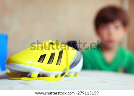 brand new yellow football boots close up photo with boy on background