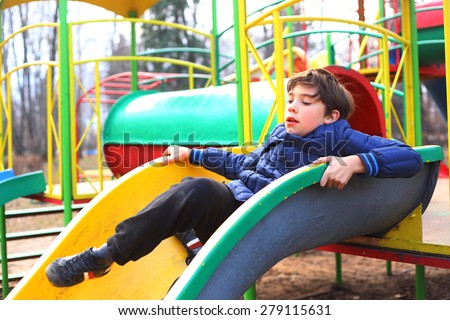 preteen handsome boy on the slide playground