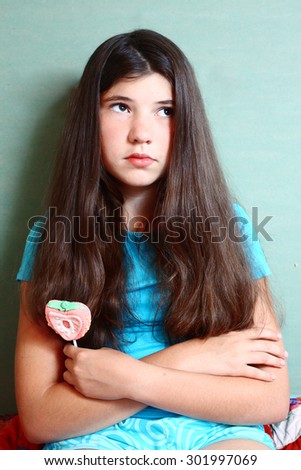 teen beautiful girl with long brown hair with candy on stick