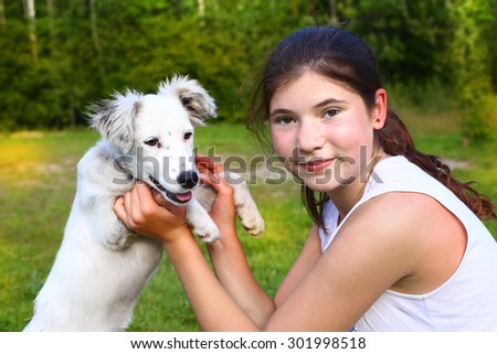 beautiful teenager girl play with white puppy on the summer forest background