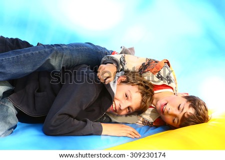 two boys play on trampoline in summer amusement outdoor park