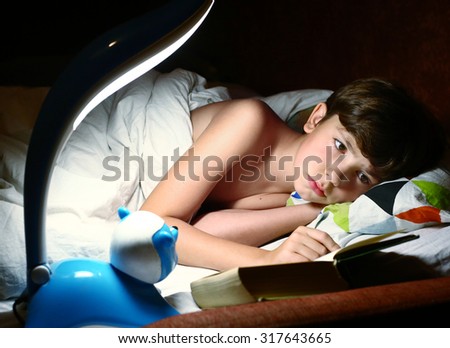 preteen handsome boy read book with lamp before sleep