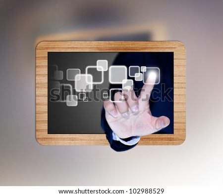 hand of business man pushing a button on a touch screen interface on black board