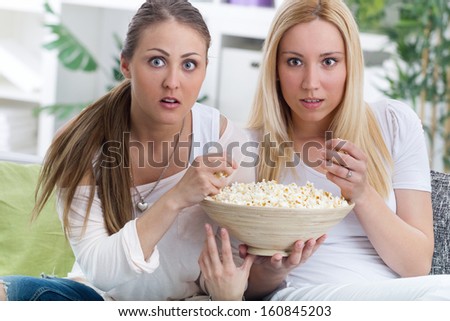 young woman watching scary movie at home