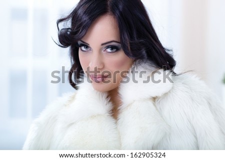 beautiful woman in a white fur coat posing