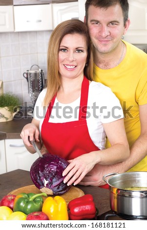 smiling husband and wife cooking together in the kitchen at home