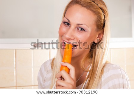 Young happy smiling woman biting raw carrots