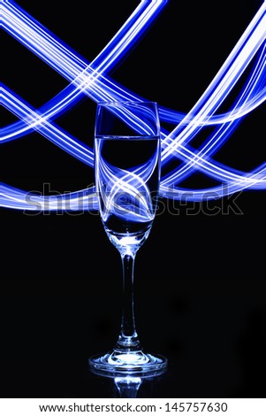 Glass of champagne with light lines abstract on black background