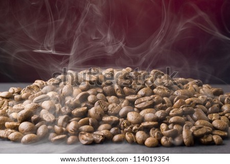 Fragrant fried coffee beans and smoke with dark background.