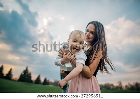 Happy together. Beautiful young mother and her son having fun at cloudy field. Wide angle photo