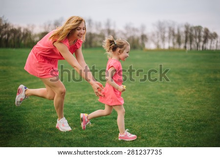 Game of tag. Happy young mother running after her daughter outdoors in park