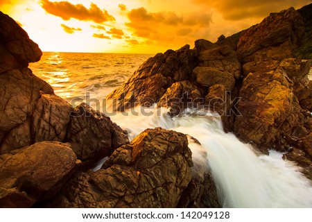 sunset sea waves line impact rock on the beach