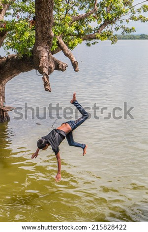 U Bein Bridge, Myanmar-Aug 26th, 2014: Myanmar children were playing by jumping from the tree at the river near U Bein Bridge where is the oldest and longest teak wooden bridge in the world.