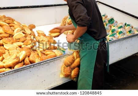 Worker in a bakery packaging white bread