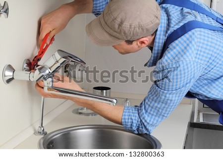 Young craftsman repairing Tap in a kitchen