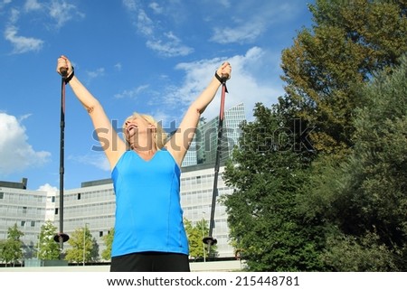 A Elderly woman with Nordic Walking poles in the Air
