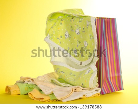 Gift package and baby clothes, on a yellow background