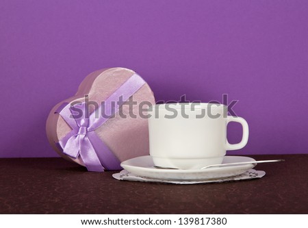 Set of tea-things and souvenir heart on a brown cloth, on a violet background