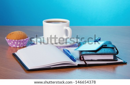 Notepad the handle an organizer a badge a cup of coffee and a cake on a table