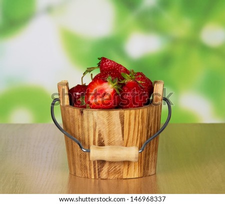 Wooden bucket of ripe fragrant strawberry on a table