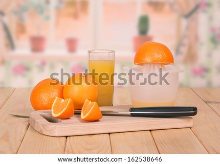 Knife, segments of orange and a juice glass against kitchen